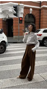 Street style εμφάνιση γυναίκας με λευκό πουκάμισο και καφέ παντελόνα με φαρδιά μπατζάκια