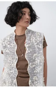 Detail shot of a brown slim-fit T-shirt layered with an intricate white floral lace vest