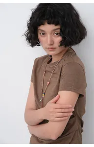 Model wearing brown slim-fit T-shirt with pleated waist and decorative necklace