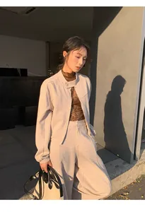 Model wearing a chic minimalist beige zip-up sweatshirt and matching trousers in sunset.