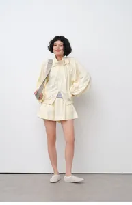 Full view of woman wearing yellow lightweight hooded sun-protection jacket and skirt set