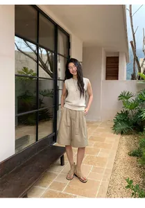 Woman wearing a cream linen blend sleeveless knit vest and tan wide-leg shorts outdoors