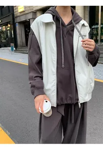 Detail view of a white faux leather vest paired with a brown hoodie in street style