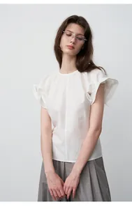 Detailweergave van vrouw in witte blouse met ruches en grijze broek met wijde pijpen
