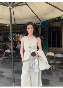 Woman in a minimalist beige cotton blend V-neck sleeveless vest and matching trousers.