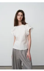 Model draagt ontspannen witte blouse en grijze wijde broek in minimalistische stijl