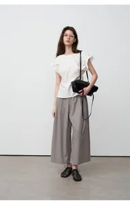 Volledig aanzicht van een grijze wijde broek gecombineerd met een witte blouse met pofmouwen.