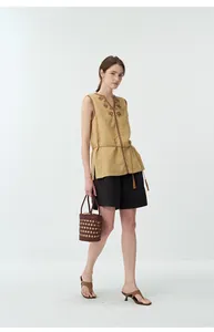 Dettaglio di un gilet in lino ricamato vintage con scollo a V e cintura con nappe fini.