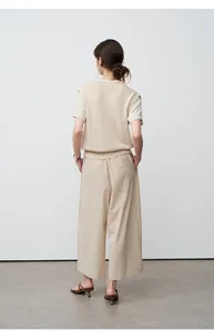 Achteraanzicht van een vrouw met een beige wijde broek in lazy-stijl en een gebreide top