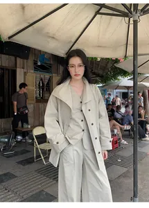 Detailed view of minimalist beige V-neck vest layering style with wide-lapel jacket