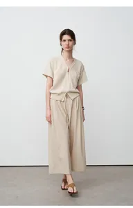 Volledige opname van een vrouw in een beige gebreid vest en bijpassende wijde broek.