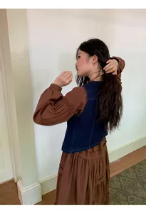 Vista dettagliata del gilet di jeans retrò indossato su un lungo vestito marrone
