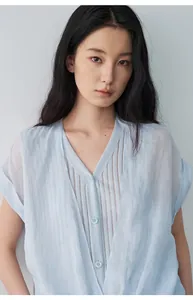 Détail d'une chemise bleu clair à col en V effet deux-en-un très douce sur un mannequin asiatique.