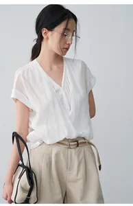 Détail d'une chemise blanche à col en V effet deux pièces portée par un mannequin asiatique