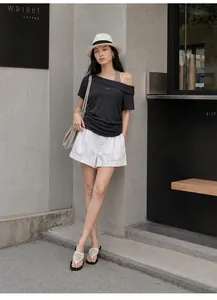 Full view showing the fit of a black off-shoulder layered T-shirt in an urban setting