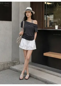 Full body street style view of charcoal off-shoulder t-shirt styled with white shorts