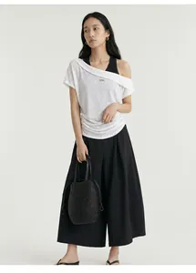 Chic off-the-shoulder white t-shirt paired with black wide-leg trousers and woven bag.