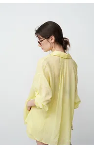 Back view of a women's oversized light yellow tencel ramie shirt in a minimalist style