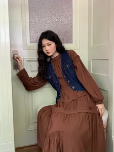 Gilet in denim retrò lavaggio scuro abbinato a un abito lungo marrone a balze da donna