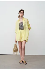 Model wearing yellow linen-style sun protection shirt and shorts set with fringe bag