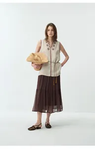Scatto intero di una donna che indossa un gilet di lino ricamato con scollo a V e gonna marrone