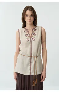 Dettaglio ravvicinato di un gilet in lino beige vintage con ricamo tribale sullo scollo a V