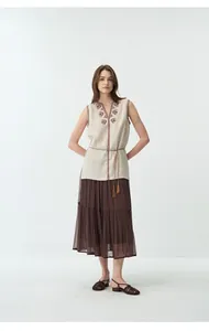 Vista intera della modella che indossa un gilet di lino ricamato con gonna a balze marrone