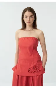 Gros plan d'un haut bustier en lin rouge avec broderies et découpes en coquillages