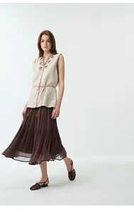 Foto a figura intera di un gilet di lino ricamato boho e gonna a pieghe