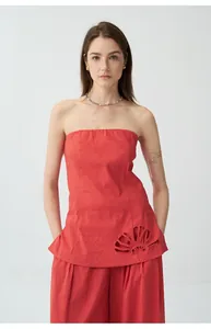 Gros plan sur un top bandeau en lin rouge avec des détails de broderies ajourées