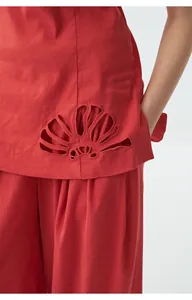 Détail d'un débardeur bandeau en lin rouge avec une broderie ajourée sur le bas