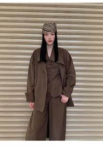 Full view of model wearing minimalist brown V-neck vest layered with matching outfit.