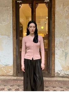 Elegant pink slim-fit knit cardigan paired with brown wide-leg pants in vintage setting.