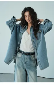 Modelo asiática con chaqueta vaquera oversize azul lavada y top de encaje blanco