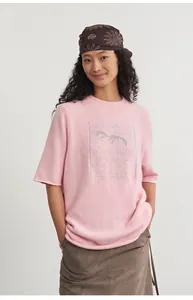 Model wearing a pink crew neck short sleeve knit top featuring silver jacquard detail