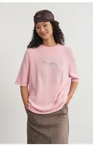 Full-length view of a model wearing a pink crewneck knit top with silver jacquard.