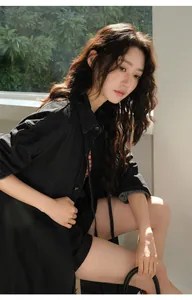 Joven modelo asiática con chaqueta vaquera negra lavada junto a una ventana con luz natural