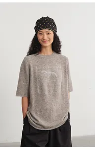 Detail view of loose beige knit top with silver jacquard horse pattern on a model