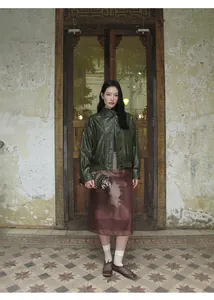 Modelo luce una chaqueta corta vintage de cuero sintético verde oscuro en un entorno retro