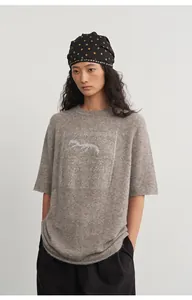 Detailed view of grey knit top with silver silk jacquard pattern and half sleeves.