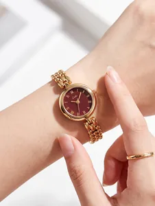 Close-up view of Gedi gold-tone watch with burgundy dial on model's wrist
