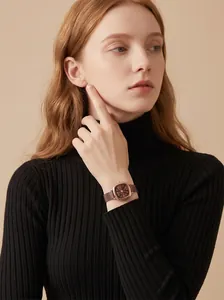 Elegante roségoldene quadratische Uhr mit braunem Zifferblatt am Handgelenk einer Frau