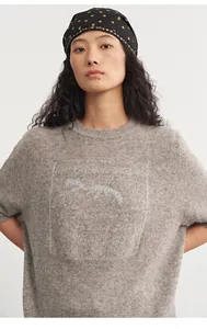 Close-up of a loose-fitting round neck knit sweater with silver jacquard detailing