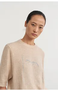 Detailed macro view of beige knit top featuring silver silk animal jacquard pattern