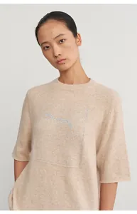 Close-up detail of beige knit top featuring silver glitter jacquard fox motif design