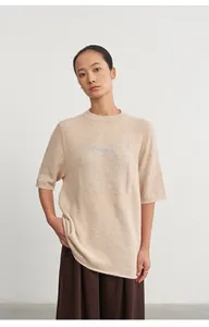 Close-up of beige knit top featuring crew neck and subtle silver thread jacquard detail