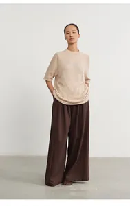 Model wearing beige round neck knit top with jacquard detail and brown wide trousers