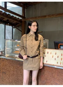 Modell trägt ein amerikanisches Retro-Hemdkleid mit Revers und Gürtel in einem Café