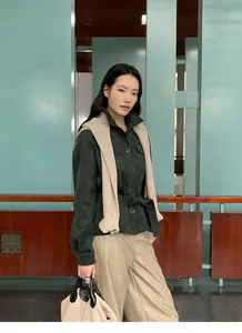 Modern women's autumn outfit featuring dark green jacket and beige wide-leg trousers