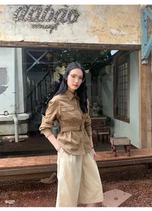 Buitenopname van een vrouw in een bruine corduroy werkjas met riem en beige korte broek